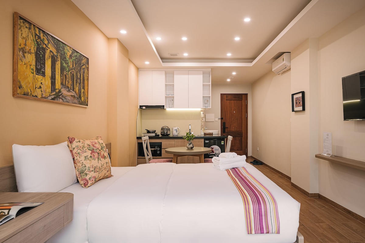 Une chambre d’hôtel équipée d’un lit, d’un bureau, d’un tableau, d’une kitchenette et d’un téléviseur.