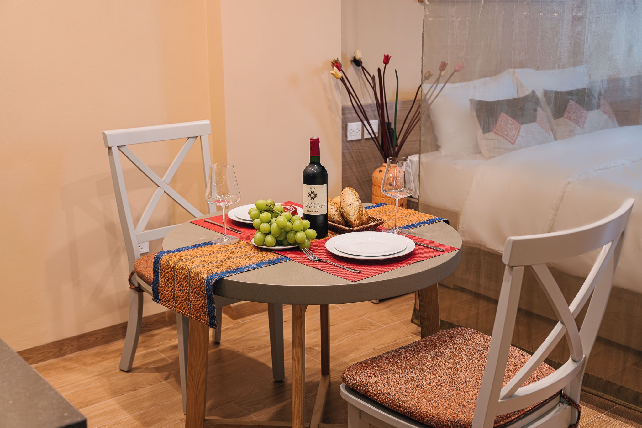 A dining table with a bottle of wine, a plate of grapes, and bread.