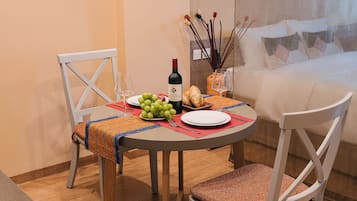 A dining table with a bottle of wine, a plate of grapes, and bread.