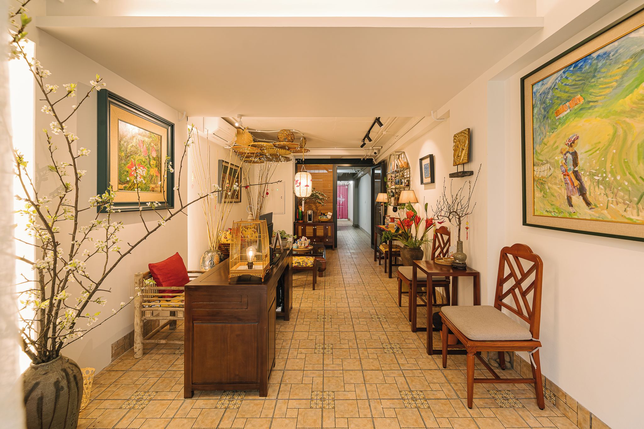 Un couloir avec un plancher en bois, un coin repas avec des chaises et des tables, et un tableau accroché au mur.