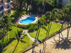 A resort with a swimming pool surrounded by palm trees and a grassy area. - Relaxing Oceanview Condo - Kealia 607 (Kihei)