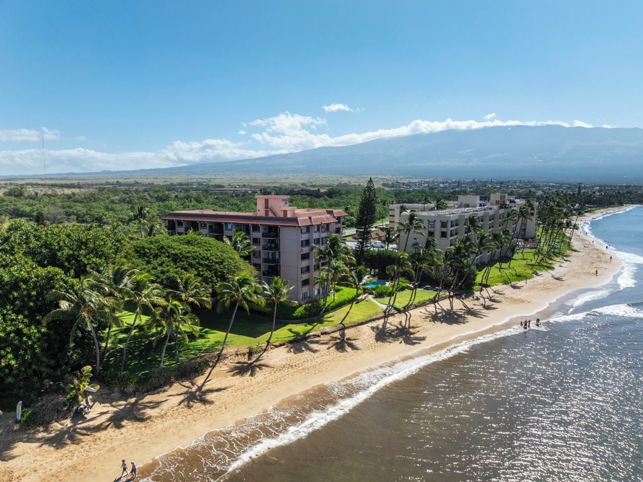 Un hôtel situé sur la côte, avec vue sur la plage, composé de plusieurs bâtiments et donnant accès à une plage de sable.