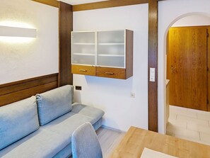 Ein Zimmer mit einem Holzschrank, einem hellen Sofa und einer Holztür.