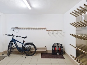 Quarto com bicicleta, armário pequeno e suporte fixado na parede.