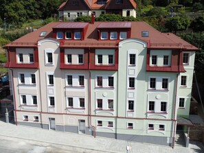 Un edificio de varios pisos con fachada simétrica, múltiples ventanas y tejado rojo.