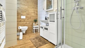 Une salle de bain moderne avec un mur en bois, une cabine de douche en verre et un lavabo blanc.