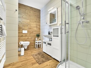 Ein modernes Badezimmer mit einer Holzwand, einer Glasdusche und einem weißen Waschbecken.