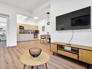 Eine moderne Küche mit Essbereich, einem flachbildfernseher an der Wand und einem runden Holztisch mit einer schwarzen Schüssel.