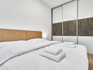 A modern hotel room with a large bed, wooden headboard, and a sliding glass door with a textured view. - Lovely apartment for 4 guests with WIFI, TV and panoramic view (Ostrov)