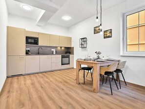 Eine moderne Küche mit integrierten Geräten, ein Essbereich mit einem Holztisch und Stühlen sowie ein Fenster mit Blick.