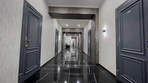 Pasillo de hotel con puertas oscuras, paredes claras y un suelo brillante.