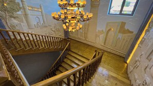 Una amplia escalera con barandilla de madera y candelabro.