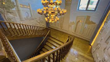 Una amplia escalera con barandilla de madera y candelabro.