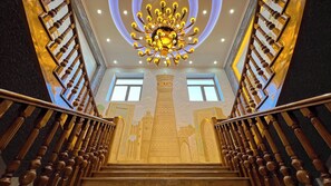Un magnifique escalier, orné d’un lustre, de rampes en bois et d’une fresque murale richement décorée.