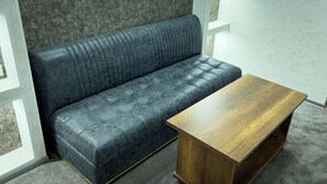 Ein dunkelblaues Sofa mit einer gesteppten Gestaltung und ein Couchtisch aus Holz mit natürlicher Oberfläche.