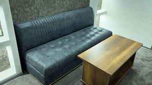 Ein dunkelblaues Sofa mit einer gesteppten Gestaltung und ein Couchtisch aus Holz mit natürlicher Oberfläche.