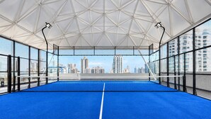 Una cancha de tenis interior con vistas despejadas de un horizonte urbano a través de la red.
