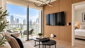 Una sala de estar moderna con un televisor grande, un sofá, una mesa de centro y vistas de la ciudad.