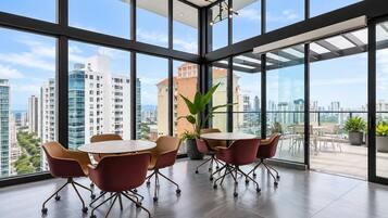 A modern conference room with a panoramic city view, large windows, and a round table with chairs.