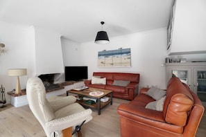 Ein Wohnzimmer mit Kamin, Fernseher, Couchtisch und Sofa.
