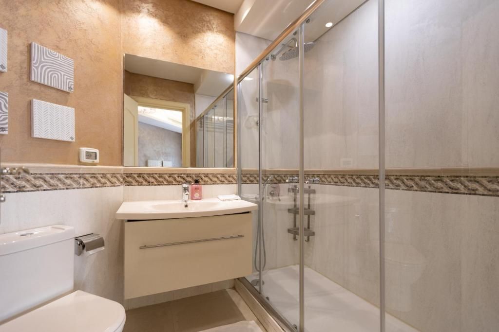 A modern bathroom with a glass-enclosed shower, a toilet, and a vanity with a mirror.