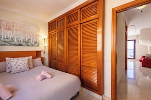 A hotel room with a bed, wooden wardrobe, a painting, and a red sofa in the adjacent room. - South-Facing Duplex in Los Cristianos (Los Cristianos)