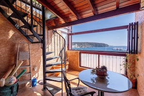 A balcony with a view of the sea, a round table, a chair, a potted plant, and a staircase. - South-Facing Duplex in Los Cristianos (Los Cristianos)