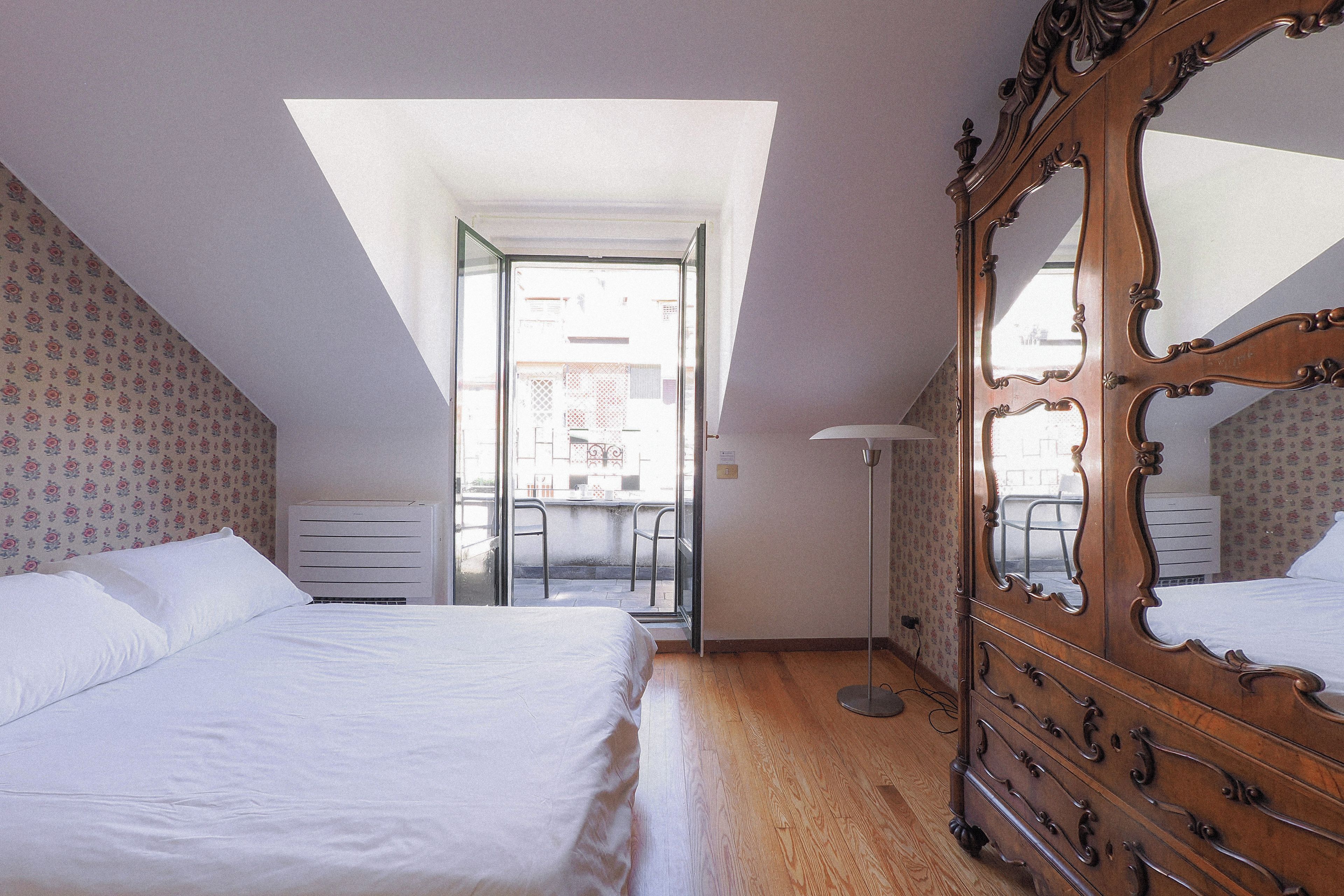 Una camera da letto con un ampio specchio, un letto, un armadio e un lucernario.