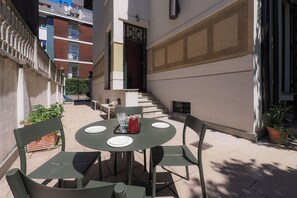 An outdoor seating area with a round table and chairs, a potted plant, and a staircase leading to an upper level. - Contempora - Casa Osti - Designer Villa with Garden in the City Center (Milano)