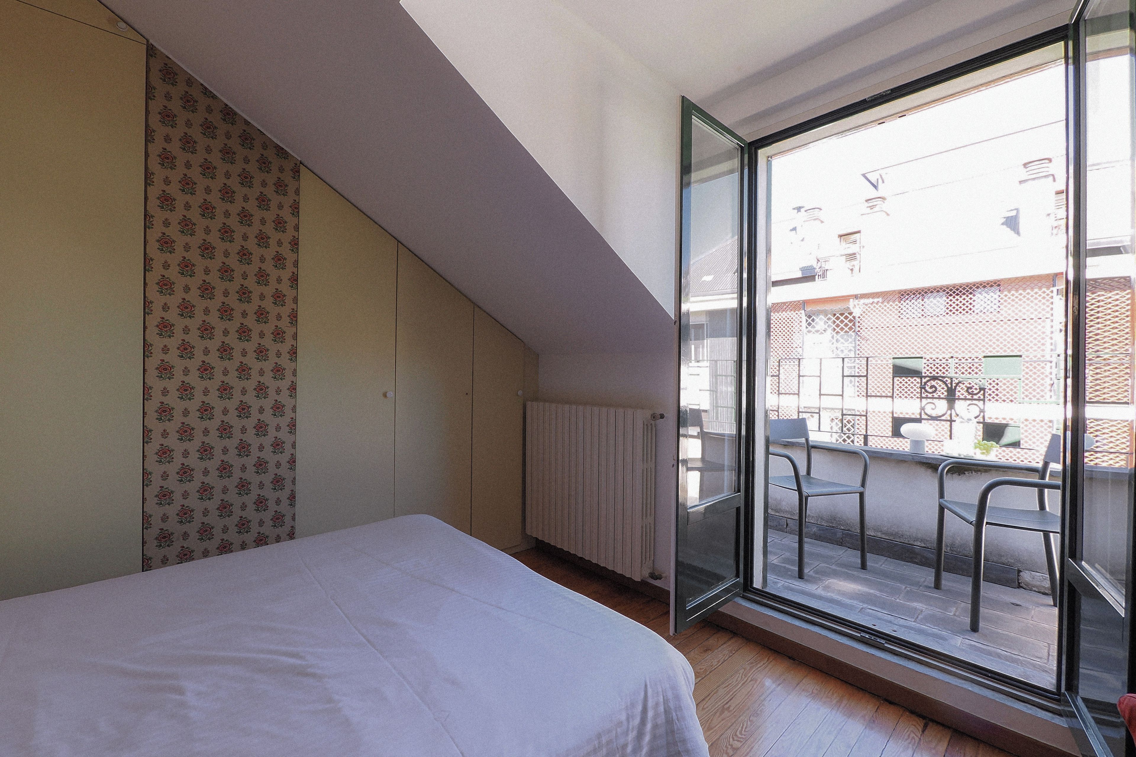 Una camera da letto con un letto, un termosifone, una finestra e vista sull'esterno.