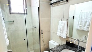 A modern bathroom with a glass-enclosed shower, a white toilet, a granite sink, and a mirror above the sink. - Pateo Rio Stay, Porto Maravilha, Rio de Janeiro. (Rio de Janeiro)