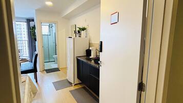 A hallway with a kitchen area, a refrigerator, and a door leading to a bathroom.