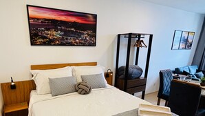 A neatly made bed with a quilted blanket, a wooden headboard, and a nightstand with a lamp. - Pateo Rio Stay, Porto Maravilha, Rio de Janeiro. (Rio de Janeiro)