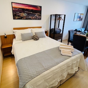 Uma cama bem arrumada com edredom acolchoado, cabeceira de madeira e mesa de cabeceira com abajur.