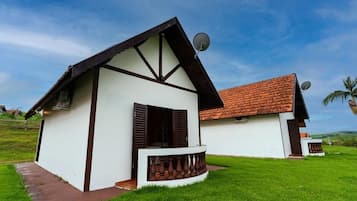 Une maison à deux étages avec un balcon, une antenne parabolique et un toit recouvert de tuiles rouges.