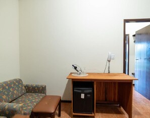 A compact living space with a sofa, a small wooden table, a bench, and a compact refrigerator. - Hotel Dona Paschoalina (Socorro)
