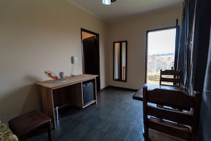 A room with a wooden desk, a small trash bin, a chair, and a view through a window. - Hotel Dona Paschoalina (Socorro)