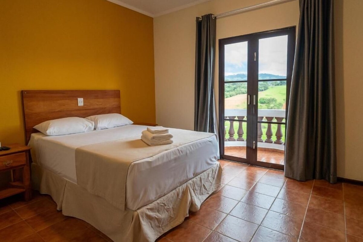 Ein Hotelzimmer mit einem Bett, einem Nachttisch und Blick auf einen Balkon.