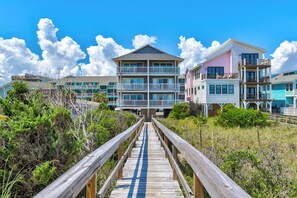 A beachfront hotel with a wooden boardwalk leading to the entrance, featuring multiple balconies and a clear view of the ocean. - 🌊La Mer | 3Br Oceanfront Condo with Shared Beach Walkover🧜‍♀️ (Carolina Beach)