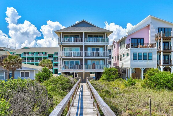 A beachfront property with a wooden boardwalk leading to a multi-story building with balconies. - 🌊La Mer | 3Br Oceanfront Condo with Shared Beach Walkover🧜‍♀️ (Carolina Beach)