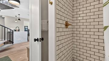 A modern interior with a kitchen area, a staircase, and a corner with a brick-patterned wall.