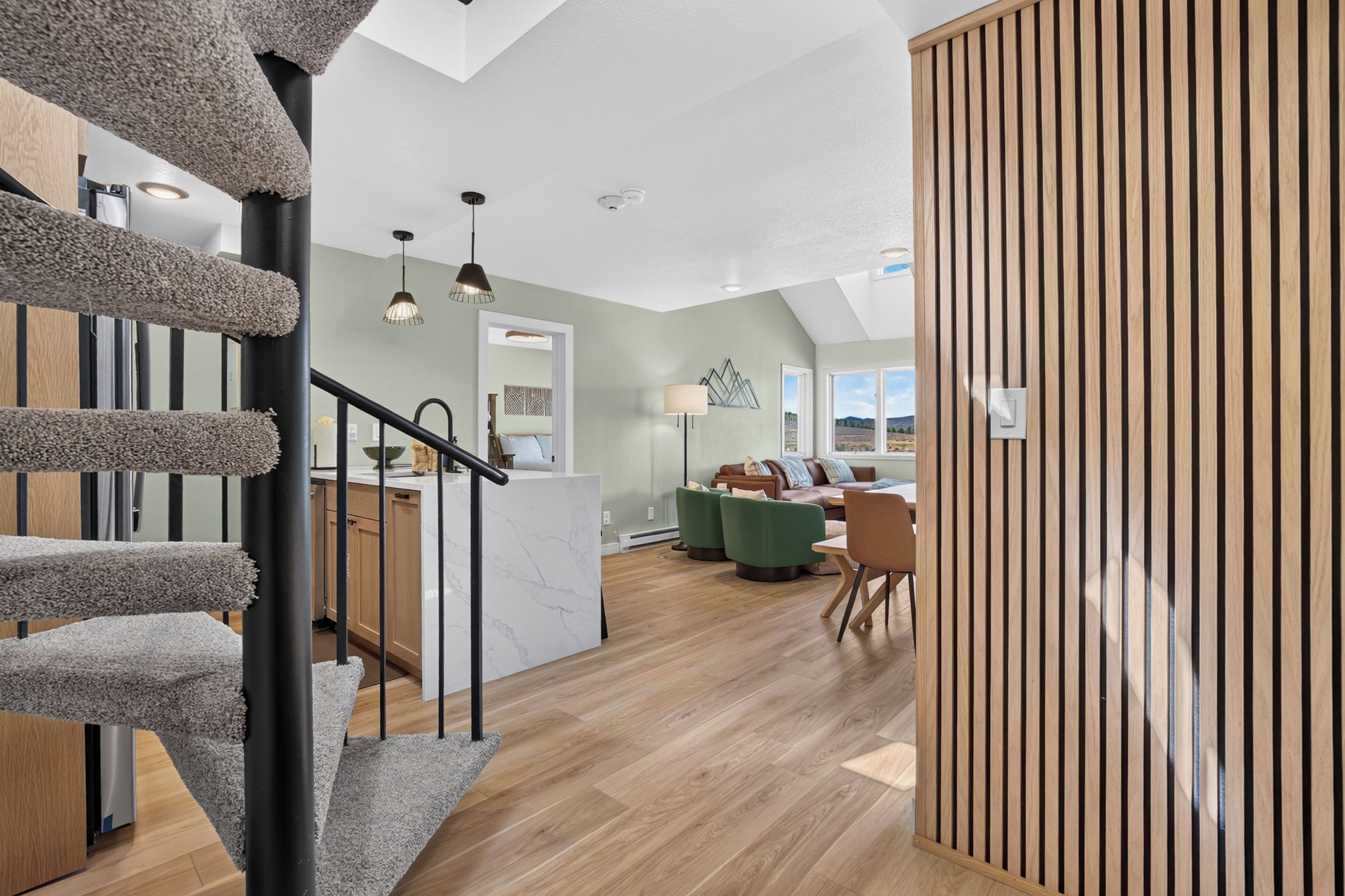 A modern interior with a staircase, a dining area, and a view through a window.