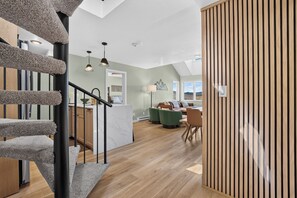 Un interior moderno con una escalera, un comedor y vistas por una ventana.
