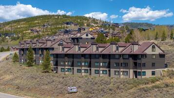 A multi-story hotel with a modern architectural design, located in a hilly area with a view of other buildings in the background.