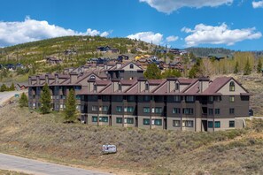 A multi-story hotel with a modern architectural design, located in a hilly area with a view of other buildings in the background. - Why You’ll Love this Colorado Escape • Ski-in/ski-out access adjacent to the Gra (Granby)