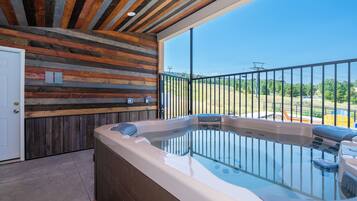 A hot tub with a wooden wall and a balcony with a metal railing.