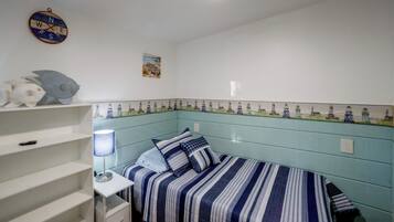 A bedroom with a bed, a shelf with decorative items, a wall clock, and a ceiling fan.