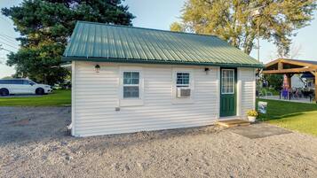 A small, single-story building with a green metal roof, a front door, and a small window.