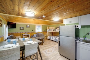 A compact kitchen with a refrigerator, a dining table with chairs, and a sofa. - Walk to Lake Ontario! 'minnow Cottage' (Kent)