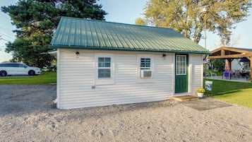 A small, single-story building with a green metal roof, a front door, and a small window.